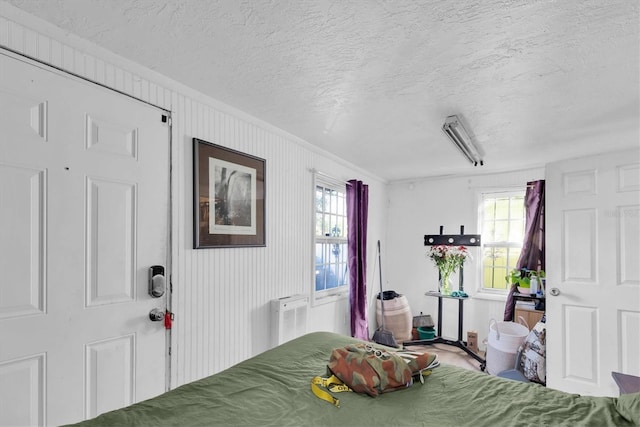 bedroom featuring a textured ceiling, crown molding, and multiple windows