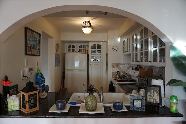 kitchen with backsplash, white fridge, hanging light fixtures, and stainless steel electric range