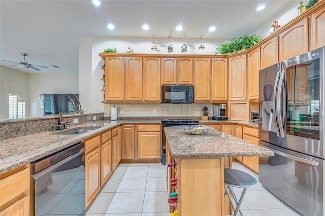 kitchen featuring black appliances, sink, ceiling fan, light tile patterned flooring, and a breakfast bar area