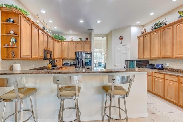 kitchen featuring a kitchen breakfast bar, decorative backsplash, stainless steel fridge, light tile patterned floors, and stone countertops