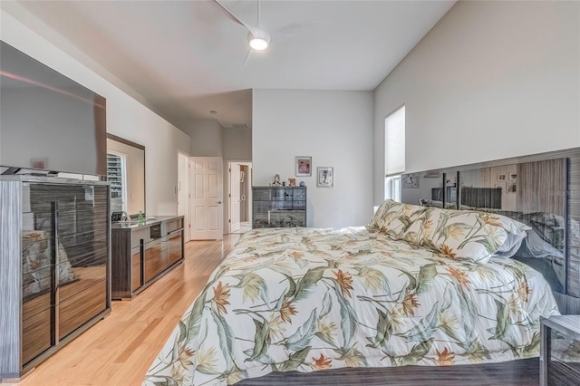 bedroom with a fireplace, light hardwood / wood-style flooring, and ceiling fan