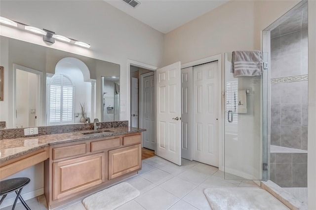 bathroom featuring tile patterned flooring, vanity, and a shower with shower door