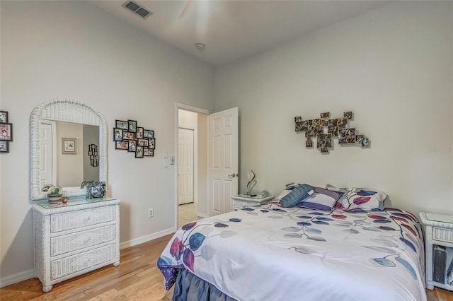 bedroom featuring a high ceiling and light hardwood / wood-style floors