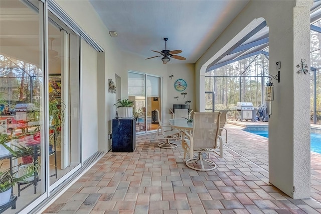 sunroom featuring ceiling fan and a swimming pool