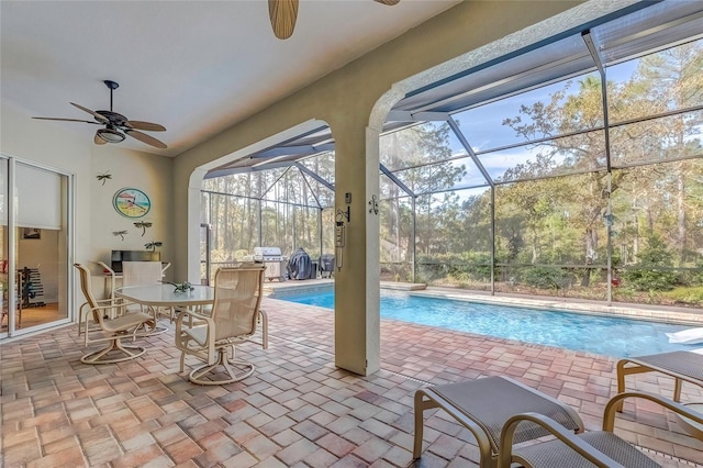 view of swimming pool with a patio, glass enclosure, ceiling fan, and grilling area