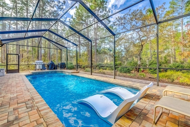 view of pool with a jacuzzi, area for grilling, a lanai, and a patio area