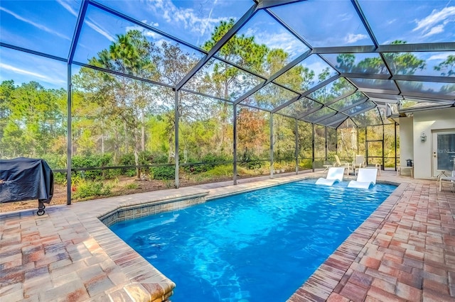 view of pool with area for grilling, a lanai, and a patio area