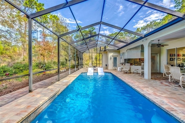 view of pool with glass enclosure, ceiling fan, and a patio