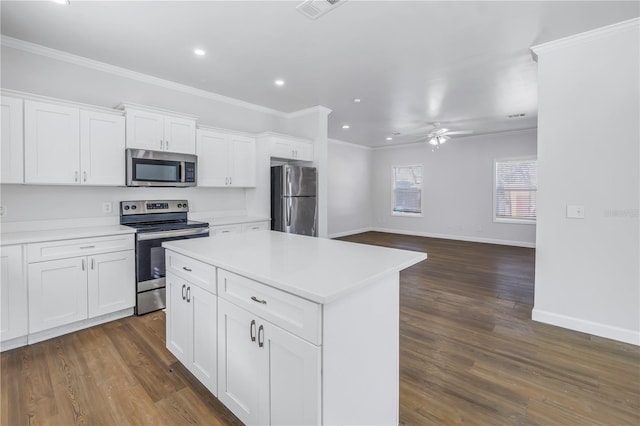 kitchen with crown molding, stainless steel appliances, white cabinets, and a kitchen island