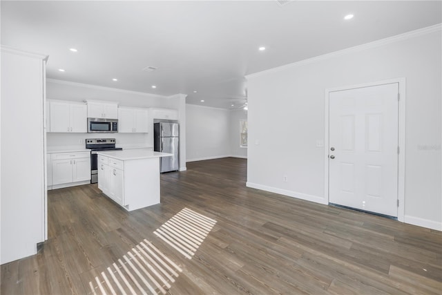 kitchen featuring dark wood-type flooring, stainless steel appliances, a kitchen island, and white cabinets