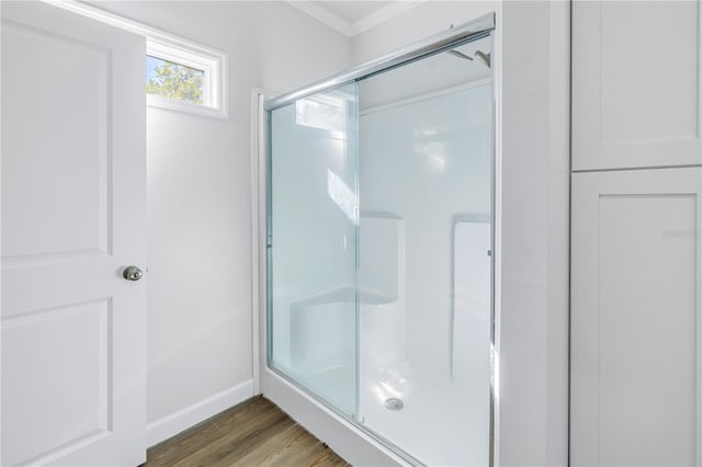 bathroom with ornamental molding, wood-type flooring, and a shower with door