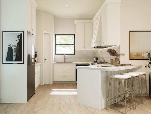 kitchen featuring sink, a kitchen breakfast bar, white cabinets, decorative backsplash, and kitchen peninsula