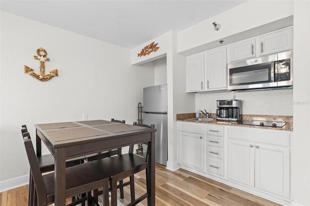 kitchen featuring white cabinetry, sink, light wood-type flooring, and appliances with stainless steel finishes