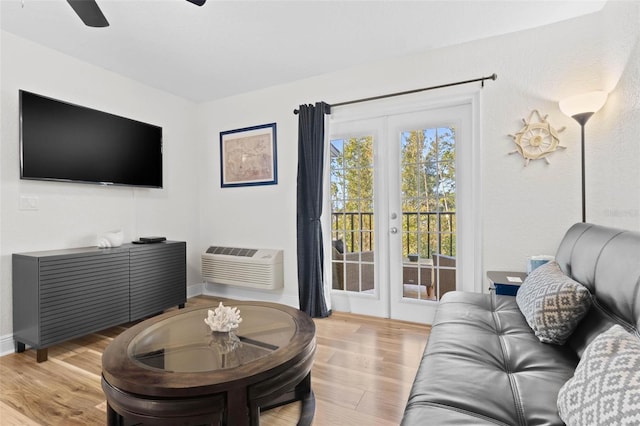 living room with a wall mounted air conditioner, light wood-type flooring, and ceiling fan