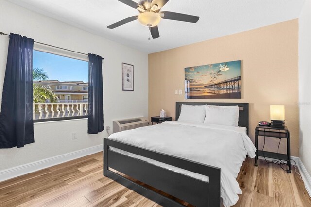 bedroom featuring light wood-type flooring, an AC wall unit, and ceiling fan