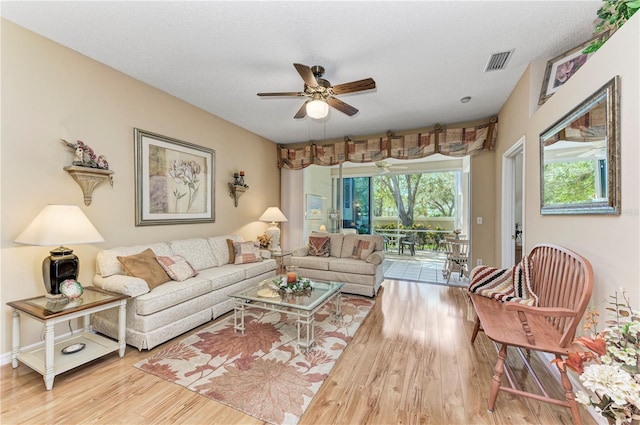 living room featuring a textured ceiling, light hardwood / wood-style flooring, and ceiling fan