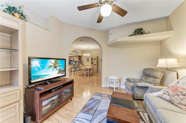 living room featuring ceiling fan with notable chandelier, a textured ceiling, and light wood-type flooring