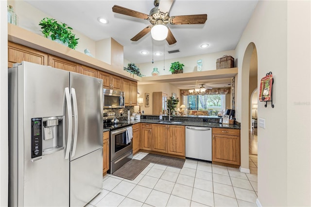 kitchen with appliances with stainless steel finishes, backsplash, dark stone counters, sink, and light tile patterned floors