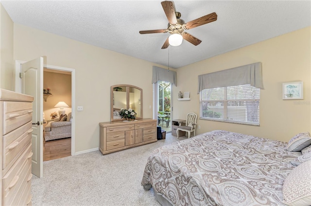 bedroom featuring ceiling fan, light colored carpet, and a textured ceiling