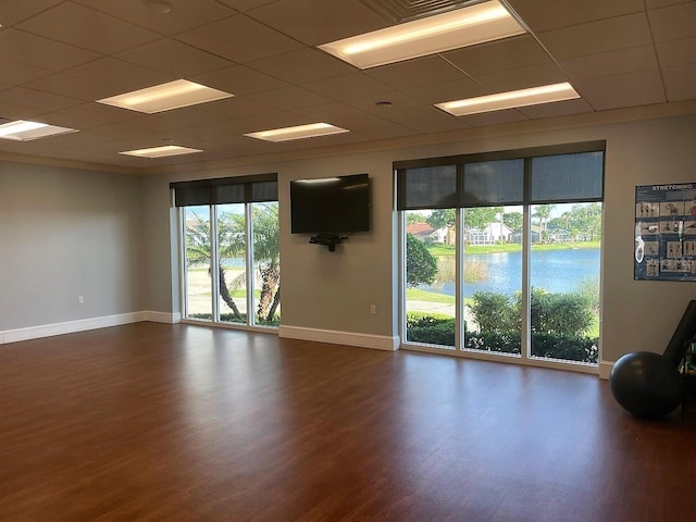 unfurnished room featuring a wealth of natural light, a drop ceiling, and dark hardwood / wood-style floors