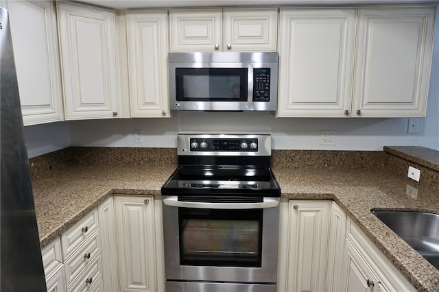 kitchen with white cabinets, stone countertops, sink, and stainless steel appliances