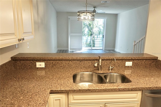 kitchen featuring ceiling fan, sink, pendant lighting, and light stone counters