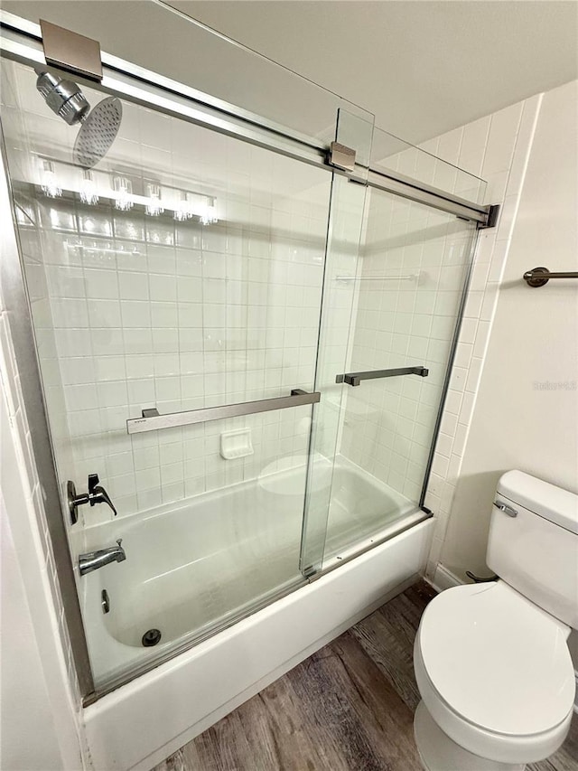 bathroom featuring toilet, bath / shower combo with glass door, and hardwood / wood-style flooring