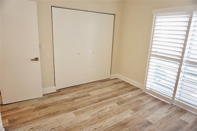 unfurnished bedroom with light hardwood / wood-style floors, a closet, and multiple windows