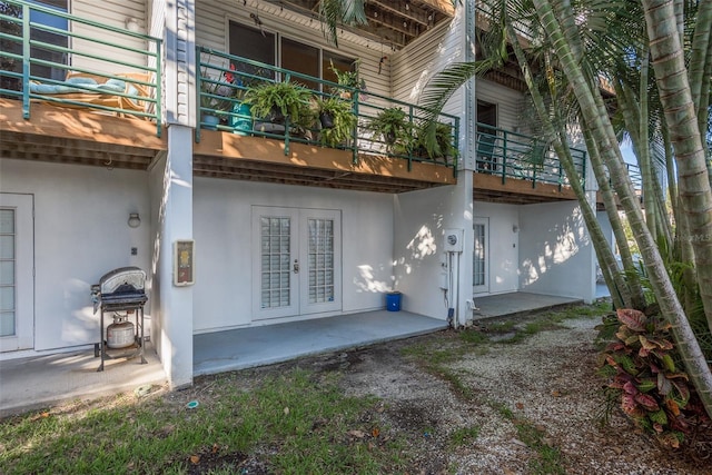 back of property featuring a balcony, a patio, and french doors