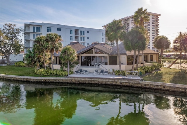 rear view of house featuring a yard, a patio, and a water view