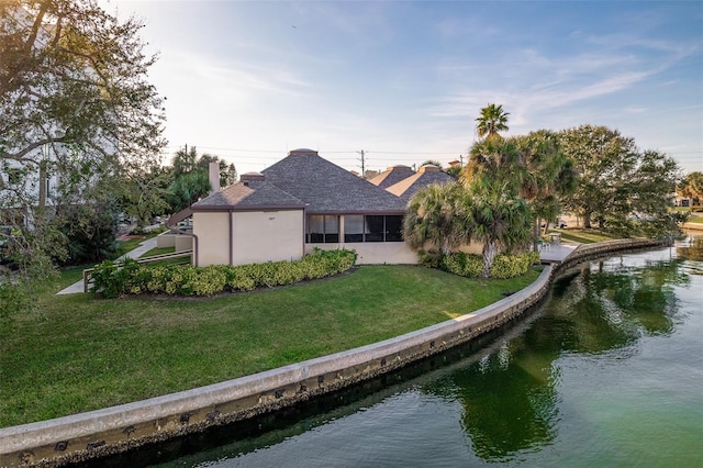 rear view of house with a water view and a yard