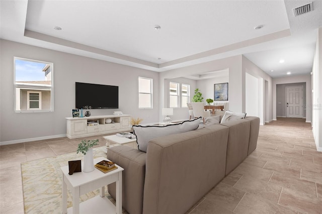 living room featuring a tray ceiling and a healthy amount of sunlight