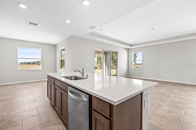 kitchen with a wealth of natural light, sink, stainless steel dishwasher, and a center island with sink