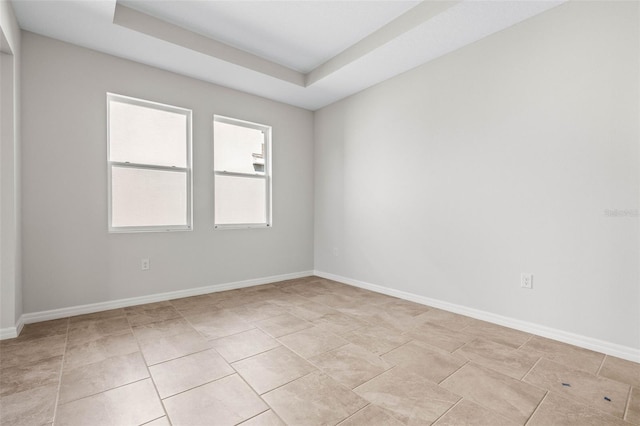 empty room with a raised ceiling and light tile patterned floors