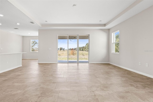 tiled spare room featuring a tray ceiling