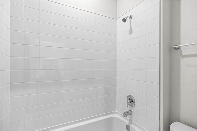 bathroom featuring tiled shower / bath combo and toilet