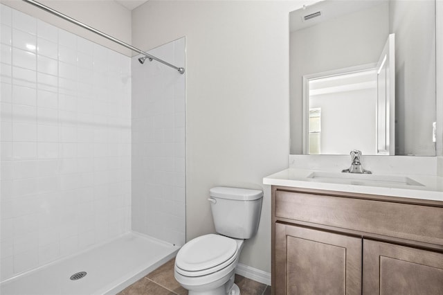 bathroom with tile patterned floors, vanity, a tile shower, and toilet