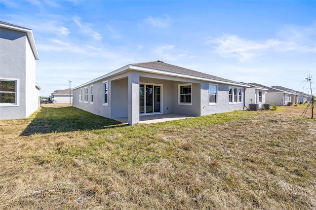 rear view of house with cooling unit, a patio area, and a lawn