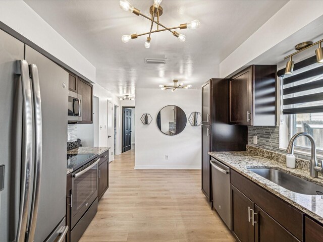 2000 57th St N, Saint Petersburg, FL 33710 - kitchen featuring sink, light wood-type flooring, light stone countertops, a notable chandelier, and stainless steel appliances