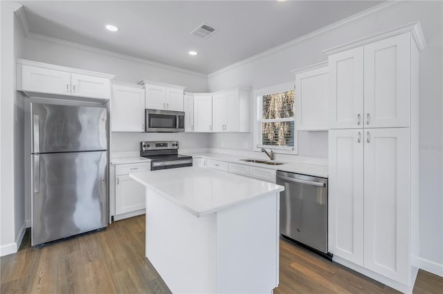 kitchen featuring sink, crown molding, appliances with stainless steel finishes, white cabinetry, and a center island