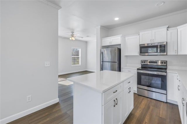 kitchen featuring dark wood-type flooring, ornamental molding, a kitchen island, stainless steel appliances, and white cabinets