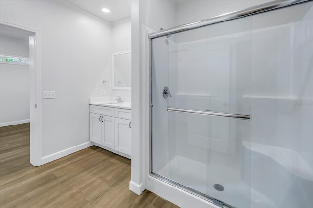 bathroom with wood-type flooring, vanity, and a shower with shower door