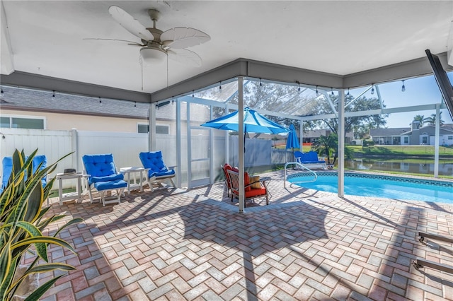 view of swimming pool with a lanai, ceiling fan, a water view, and a patio