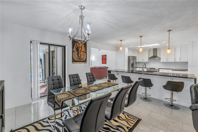 dining space featuring a textured ceiling, sink, and a chandelier