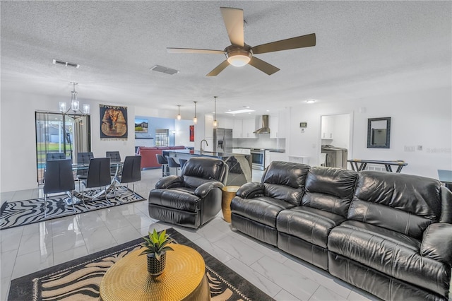 living room featuring a textured ceiling, ceiling fan with notable chandelier, and sink