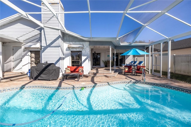 view of pool with glass enclosure, a patio, and grilling area