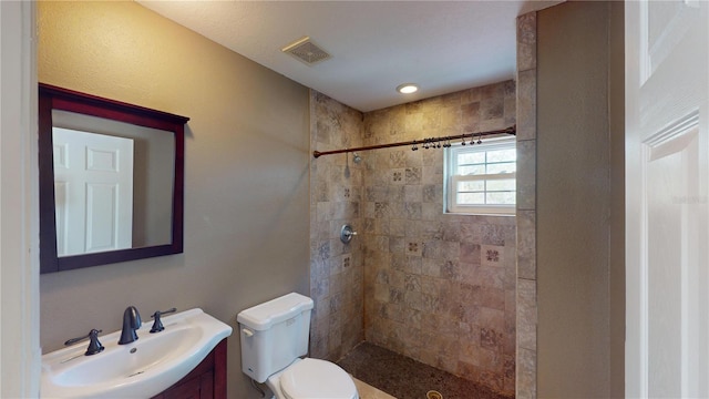 bathroom with vanity, toilet, and tiled shower