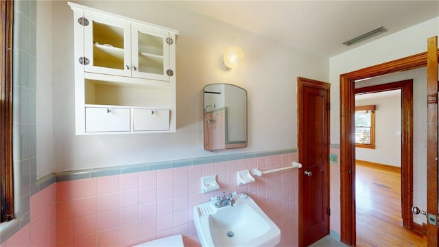 1149 Sedeeva St, Clearwater, FL 33755 - half bathroom with tile walls, a wainscoted wall, a sink, visible vents, and wood finished floors