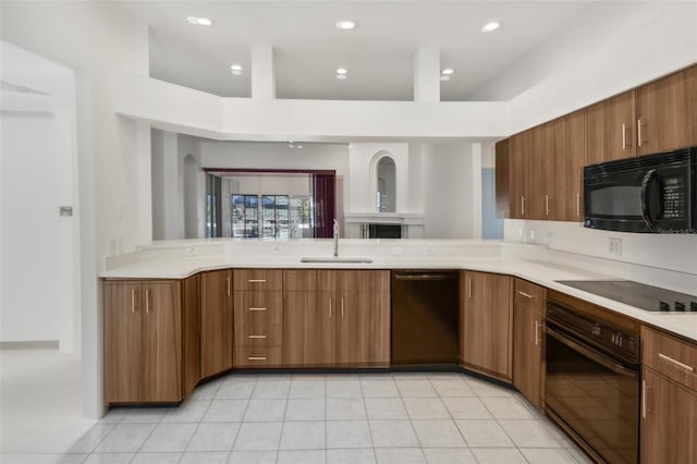 kitchen with black appliances, kitchen peninsula, and sink