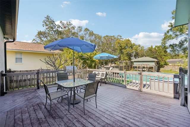 wooden deck with a fenced in pool and a grill